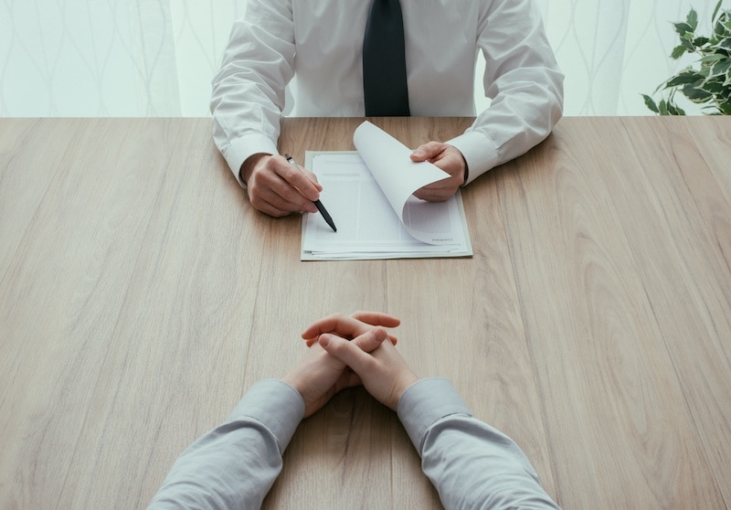 Examiner reading a resume during a job interview, employment and recruitment concept, point of view shot